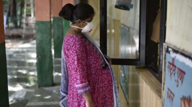 Uma mulher grávida espera em frente da janela de registo para um teste Covid-19, num centro da escola primária MCD no Portão de Turkman a 24 de Junho de 2020 em Nova Deli, Índia.