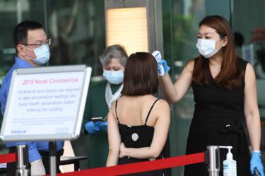 Building management staff conduct temperature screenings of visitors and tenants of a building in the financial district of Singapore on 10 February 2020