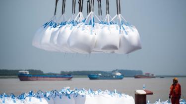 This photo taken on August 7, 2018 shows workers unloading bags of chemicals at a port in Zhangjiagang in China's eastern Jiangsu province