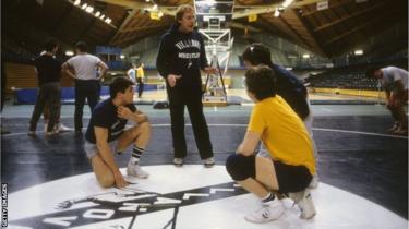 A wrestling coach instructing young athletes.