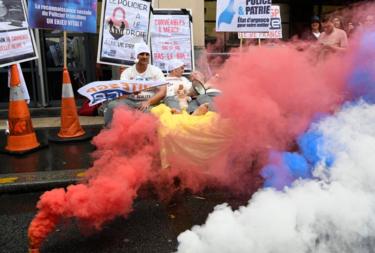 Police surrounded by coloured smoke at a protest