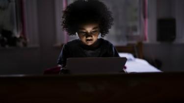 Child surfing internet on a computer tablet in his bedroom
