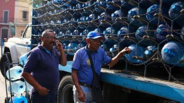 Workers deliver water bottles in Caracas on March 27, 2019 during a power outage in Venezuela