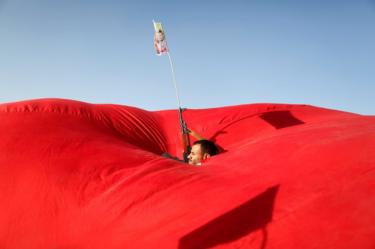 A Houthi follower emerges from a gap in a flag.