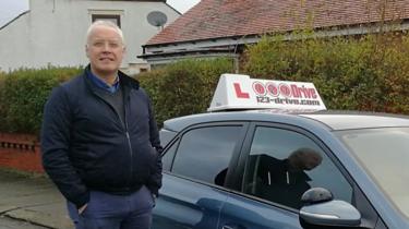 Bob Coughtrey de pie junto a su coche