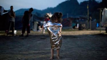 Refugee girl wrapped in a space blanket in Greece