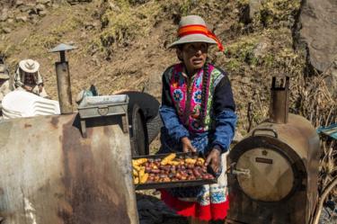 Una mujer cocina papas para complementar los platos principales para alimentar a la multitud