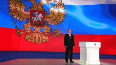 Vladimir Putin stands on stage during annual address