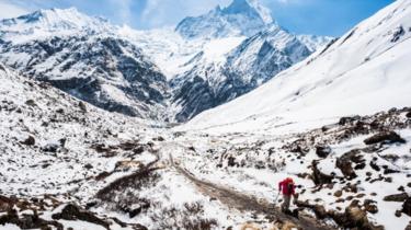 A trekker walks to the Annapurna base camp with Mount Machapuchare in the background