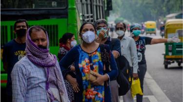 Indische Pendler mit Gesichtsmasken warten auf öffentliche Verkehrsmittel am 09. Juli 2020 in Neu-Delhi, Indien.