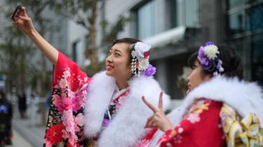 Donne che indossano il kimono si scattano un selfie partecipando a una cerimonia di passaggio di età l'8 gennaio 2018 a Yokohama, Giappone.