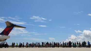 Evacuees queue to board a plane