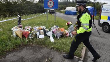 A police officer lays flowers at the scene where PC Andrew Harper was killed