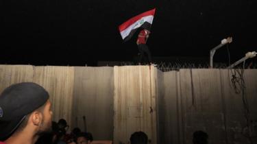 معترضان پرچم عراق را روی دیوار کنسولگری ایران در عراق بالا بردند