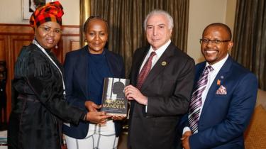 Temer segura o livro "The prison letters of Nelson Mandela" (As cartas da prisão de Nelson Mandela, em tradução literal), em foto com a ministra de desenvolvimento de pequenos negócios, Lindiwe Zulu (à esquerda), com Ndileka Mandela, Neta de Mandela, e com o CEO da Fundação Mandela, Sello Hatang, tirada em Joanesburgo