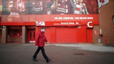 A worker walks by Anfield Stadium, the home of Liverpool Football Club