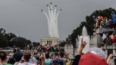 People react to a military flyover while President Donald Trump gives his speech during Fourth of July festivities in 2019