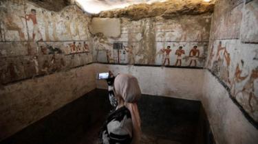 A woman takes a photo inside the tomb of an Old Kingdom priestess adorned with well-preserved and rare wall paintings on the Giza plateau in Cairo that was unveiled on 3 February 2018