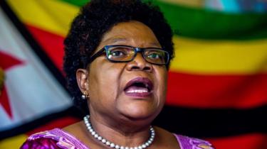 Joice Mujuru speaking in front of flags