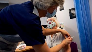 En kvinde får en Pfizer/BioNtech-vaccine i England