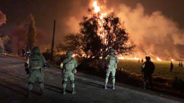 Army personnel look over site of large fire