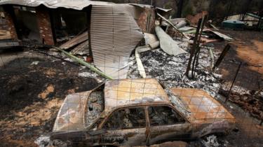 Egy autó és egy ház elszenesedett maradványai a bozóttűz után a Victoria állambeli Kinglake-ben