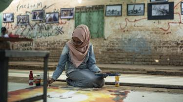 un artist care lucrează la o rolă de pânză la Centrul de formare profesională din Khartoum, Sudan