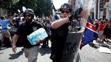 A far-right protester clutches a black shield