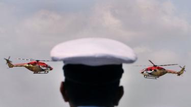 An Indian air force officer watches helicopters perform in an air show