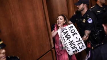 A woman protests as US Supreme Court nominee Brett Kavanaugh arrives on the first day of his confirmation hearing