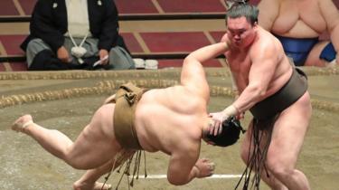 Hakuho îl împinge în jos pe adversarul Kagayaki în ring în timpul Marelui Turneu de Sumo de la Tokyo, în iulie 2020.