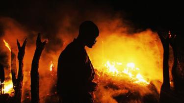 Een Soedanese rebellenstrijder van de Justice and Equality Movement (JEM) kijkt somber toe hoe het verlaten dorp Chero Kasi afbrandt, minder dan een uur nadat Janjaweed militieleden het in brand staken in de door geweld geteisterde Darfur regio op 7 september 2004.