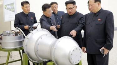 Le président Nord Coréen Kim Jong-un discute avec ses associés devant ce qui apparait comme la bombe à hydrogène