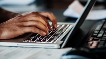 Close up of a pair of hands typing on a laptop