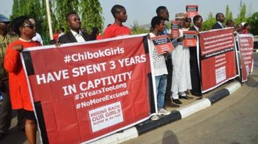 Os manifestantes seguram cartazes durante uma manifestação que assinala o terceiro aniversário do rapto das raparigas Chibok em Abuja, a 14 de Abril, 2017