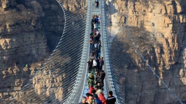 Turister går på den glasbundede hængebro i Hongyagu Scenic Area den 26. december 2017 i Pingshan i Hebei-provinsen i Kina.