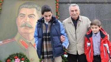 El nieto de José Stalin, Yevgeny Dzhugashvili, (centro) posa con sus nietos junto a un retrato de su famoso pariente en la plaza central de Gori, a unos 80 kilómetros de Tiflis (21 de diciembre de 2009)