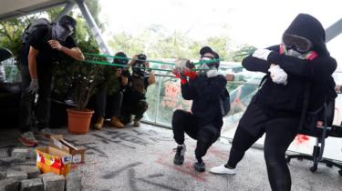 Demonstrators use a band to propel a rock during an anti-government protest