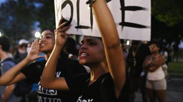 People yell at a line of police officers during a protest outside the Kenosha County Courthouse after a Black man, identified as Jacob Blake,