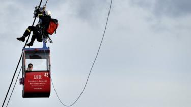 German fire crews evacuate dozens of passengers from suspended cable cars that run over the river Rhine after a gondola ran into a support pillar in Cologne, Germany, 30 July 2017