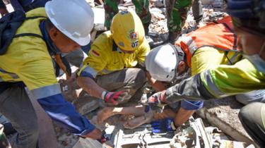 Rescue workers remove a woman alive from the rubble of a building in Tanjung, North Lombok (7 Aug 2018)