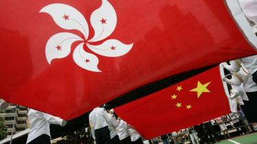 Desfile de crianças em idade escolar com enormes bandeiras chinesas e de Hong Kong durante as comemorações do 10º aniversário da entrega do domínio britânico.