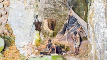 A model depiction of primitive cave life: a group of hominids are cooking by a fire and drying out pelts