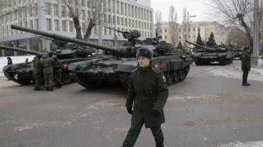 Militærperson går foran T-90 kampvogne