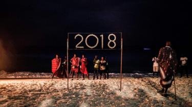 People wait for a moment to light a sign that reads 2018 during the New Year's Eve celebration on Nungwi Beach in Zanzibar, Tanzania, on December 31, 2017. / AFP PHOTO / GULSHAN KHAN (Photo credit should read GULSHAN KHAN/AFP/Getty Images)