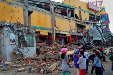 People stand in front of a damaged shopping mall after an earthquake hit the city of Palu, on Indonesia's Sulawesi Island