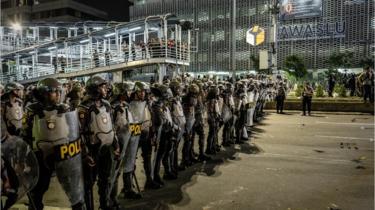 Indonesian police stand guard block protesters during a demonstration in front of the Elections Supervisory Agency