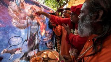 زعيم جماعة هندية قدحًا من بول البقر إلى رسم كرتوني على هيئة شيطان "لتهدئته"