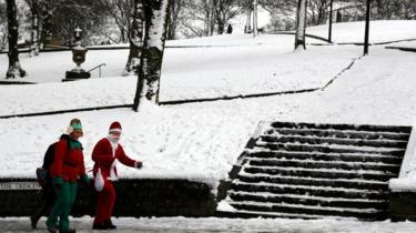 Santa and her elf tackle the snow in Buxton, Derbyshire