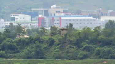 en nordkoreansk vaktpost (C) står framför det interkoreanska industrikomplexet i Kaesong (bakgrund) sett från vapenvila byn Panmunjom i den demilitariserade zonen som delar de två Korea i juli 22, 2015